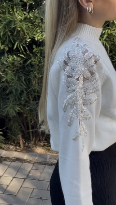 Sweater largo con diseño de strass en los hombros que caen por la manga. Cuello alto.