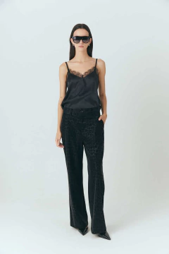 Pantalón de mujer estilo felino de color negro con estampado de leopardo, corte ancho y detalle de botón en la parte frontal.