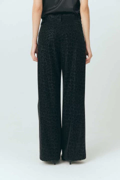 Pantalón de mujer estilo felino de color negro con estampado de leopardo, corte ancho y detalle de botón en la parte frontal.