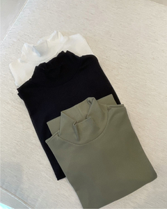 Conjunto de tres poleras LEXIE en colores blanco, negro y verde oliva apiladas sobre una superficie clara.
