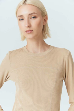Remera Laurel de color beige, con un diseño de manga larga y textura acanalada, vista frontal de una mujer con cabello corto.