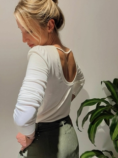 Modelo usando una remera blanca LUCY con un diseño de espalda abierta