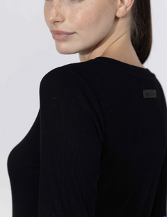Modelo usando una remera negra de manga larga, vista lateral mostrando el detalle del tejido.
