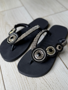 Sandalias hawaianas negras con adornos brillantes en la parte superior.