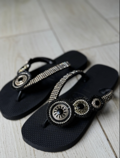 Chinelas hawaianas negras decoradas con detalles brillantes en forma de círculos.