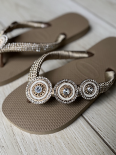 Chinelas Hawaiana Beige Dorado con detalles decorativos en la tira y pedrería brillante.