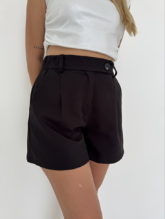 Shorts negros de mujer con cintura alta y botón, combinados con una blusa gris brillante.