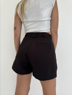 Vista trasera de un short negro con cintura elástica, combinado con una blusa plateada.