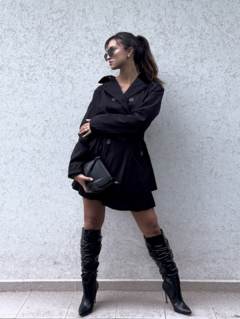 Trench Negro corte medio, con detalle de botones y cinturón en la cintura.