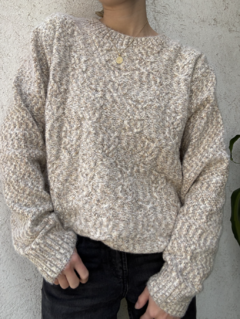 Sweater tejido color arcilla con diseño de trenzas y cuello redondo, combinado con pantalón negro
