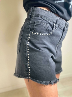 Shorts oscuros con detalles de strass en el lateral y terminación deshilachada.