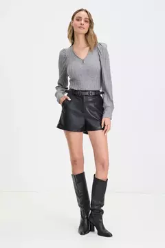 Short engomado negro, con doblés en la parte inferior. Bolsillos a los laterales y cinto con doble ebilla metálica a tono.