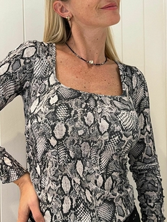 Remera de mujer con estampado de reptil en tonos negros y grises, de manga larga y escote cuadrado.