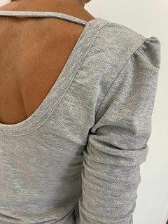 Vista posterior de una remera gris LUCY, mostrando el diseño del escote y las mangas.