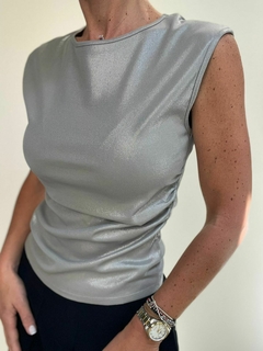 Musculosa Ray en tono plateado, con mangas cortas y un diseño ajustado, vista desde un lado, resaltando la textura del tejido.