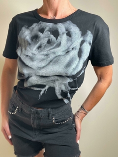 Remera negra con diseño de rosa en el frente, acompañada de shorts de denim.