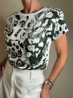 Remera Malba con estampado en tonos verdes y blanco, combinada con pantalones claros.