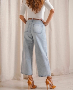 Vista trasera de un jean de Zara con cinto, color claro, combinado con una blusa de manga larga y tacones altos.