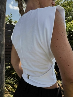 Musculosa blanca de mujer con detalle en la espalda, vista desde atrás, en un entorno natural.