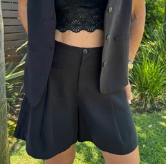 Short espinela de color negro, combinada con un top de encaje, presentada en un entorno natural con vegetación.