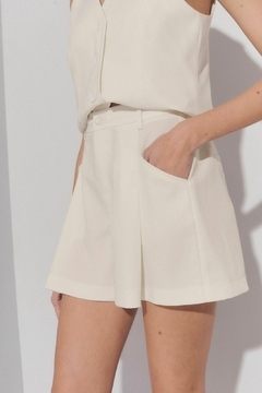 Shorts cortos de color blanco con bolsillos, combinados con una blusa sin mangas.