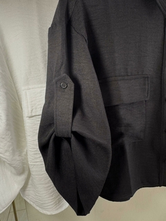 Camisa Fresia de color negro con un diseño moderno, mostrando la manga y un bolsillo frontal.