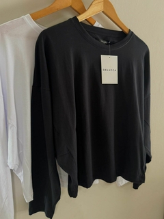 Remera Barry de color negro colgando junto a una remera blanca, ambas en perchas.
