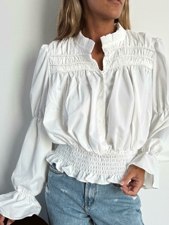 Camisa blanca de mujer con mangas voluminosas y detalles fruncidos en el pecho y la cintura.