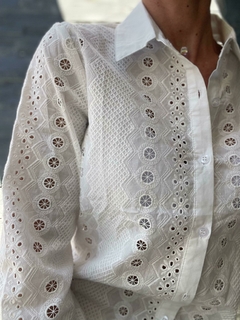 Camisa blanca de mujer con detalles bordados y mangas largas, parte de la nueva colección de otoño/invierno.