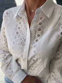Camisa blanca de mujer con detalles bordados y mangas largas, parte de la nueva colección de otoño/invierno.