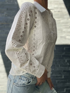 Camisa blanca de mujer con detalles bordados y mangas largas, parte de la nueva colección de otoño/invierno.