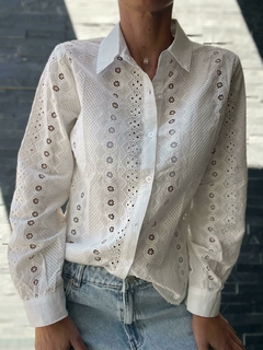 Camisa blanca de mujer con detalles bordados y mangas largas, parte de la nueva colección de otoño/invierno.