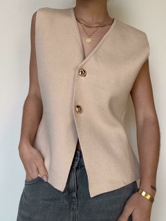 Chaleco Volcán de color beige con botones dorados, usado sobre una blusa gris.