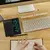 Calculadora científica com display de escrita, teclado e caderno em uma mesa de madeira