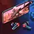 Fones de ouvido Bluetooth M28 TWS com luzes vermelhas ao lado de um smartphone exibindo um jogo de tiro.