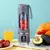 Espremedor portátil de carregamento USB em fundo colorido, com frutas frescas dentro e ao redor.