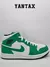 Zapatilla Air Jordan 1 Mid en color verde y blanco, con detalles en negro y logo de Jordan.