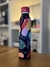 Botella de agua deportiva de aluminio con diseño colorido de hojas y formas abstractas, tapa roja, sobre una superficie de madera.