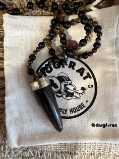 Collar con cuerno de asta , el cuerpo del mismo esta confeccionado con piedras obsidianas naturales y piedra ojo de tigre natural de 6mm. Cierre en mosqueton de acero quirurgico. 