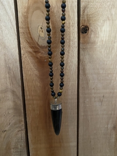 Collar con cuerno de asta , el cuerpo del mismo esta confeccionado con piedras obsidianas naturales y piedra ojo de tigre natural de 6mm. Cierre en mosqueton de acero quirurgico. 