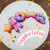 Toppers decorativos de festa do pijama, incluindo um pijama rosa, uma estrela, um travesseiro e um par de pantufas, sobre uma superfície branca com confetes amarelos.