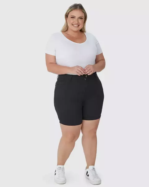Bermuda feminina plus size de sarja com elastano, cintura média, na cor preta, modelando uma mulher sorridente que usa uma camiseta branca e tênis.