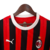 Camisa de torcedor do Milan 24/25, listrada em preto e vermelho, com logo da Puma e do AC Milan.