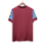 Camisa masculina vermelha do West Ham, vista traseira, com detalhes em azul e logo na manga.