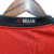 Detalhe da gola da camisa AC Milan Home 23/24, mostrando o logotipo em preto e vermelho.