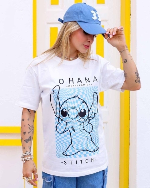 Imagem de uma jovem usando uma camiseta branca com estampa do personagem Stitch, com a frase "OHANA MEANS FAMILY", e um boné azul.