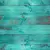Tablero de madera pintado en color aqua, con textura visible y detalles desgastados.