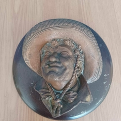 Escultura em metal aparentemente cobre sobre base de madeira na internet