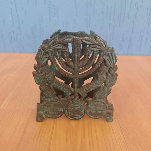Peça em metal porta guardanapocomposto por uma menorá (candelabro judaico) envolta por ramo de oliveira