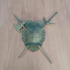 Brasão medieval com escudo central em bronze